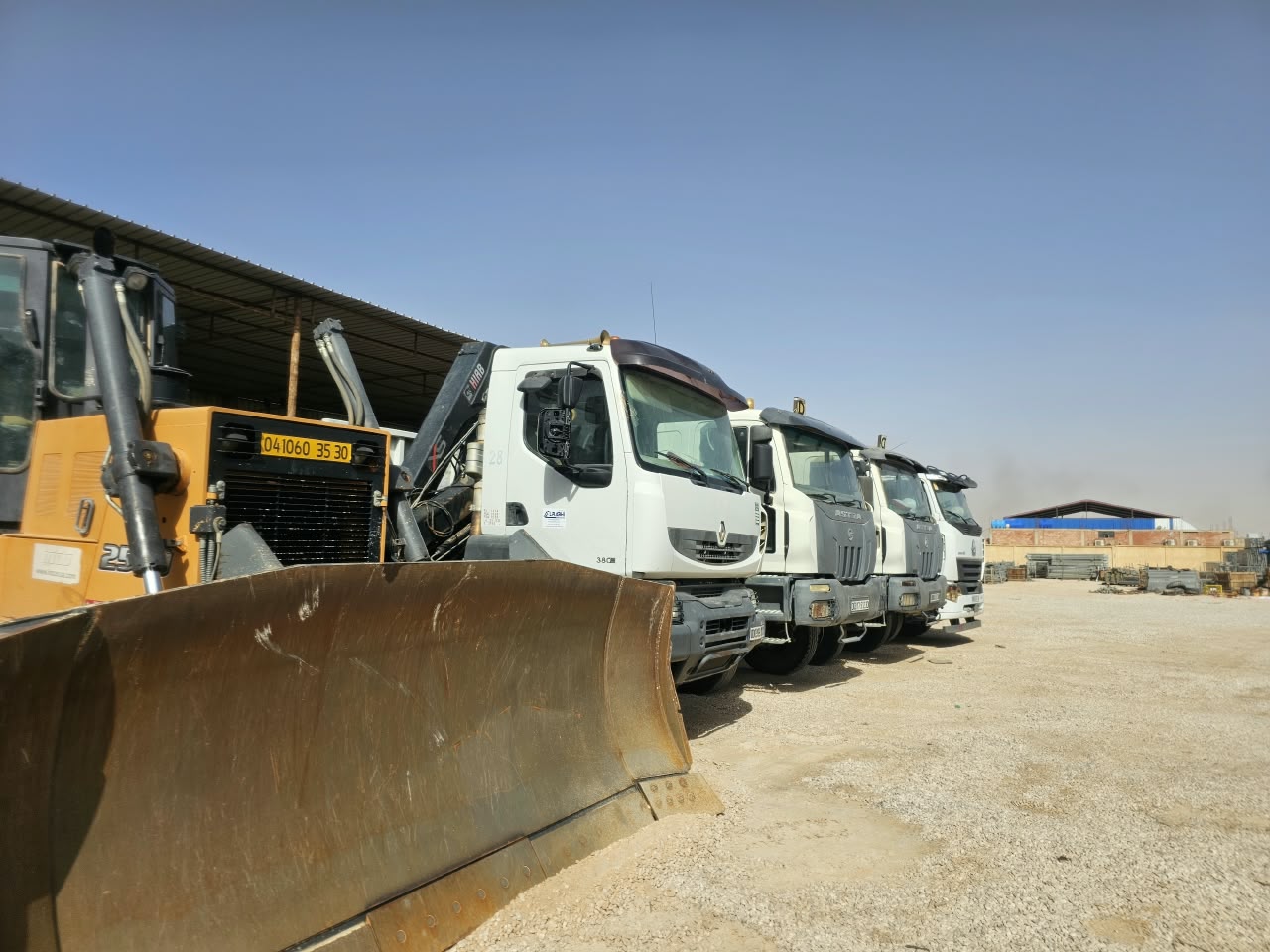 Lame de bulldozer devant une rangée de camions