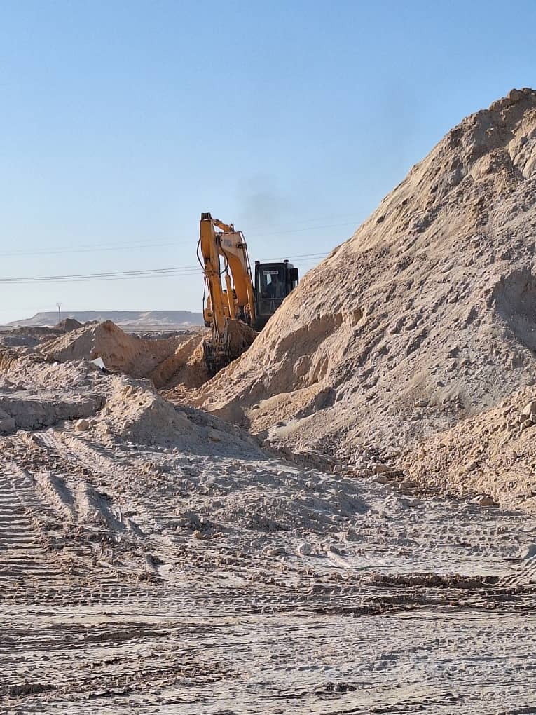 Pelle en excavation entre deux dunes de déblais
