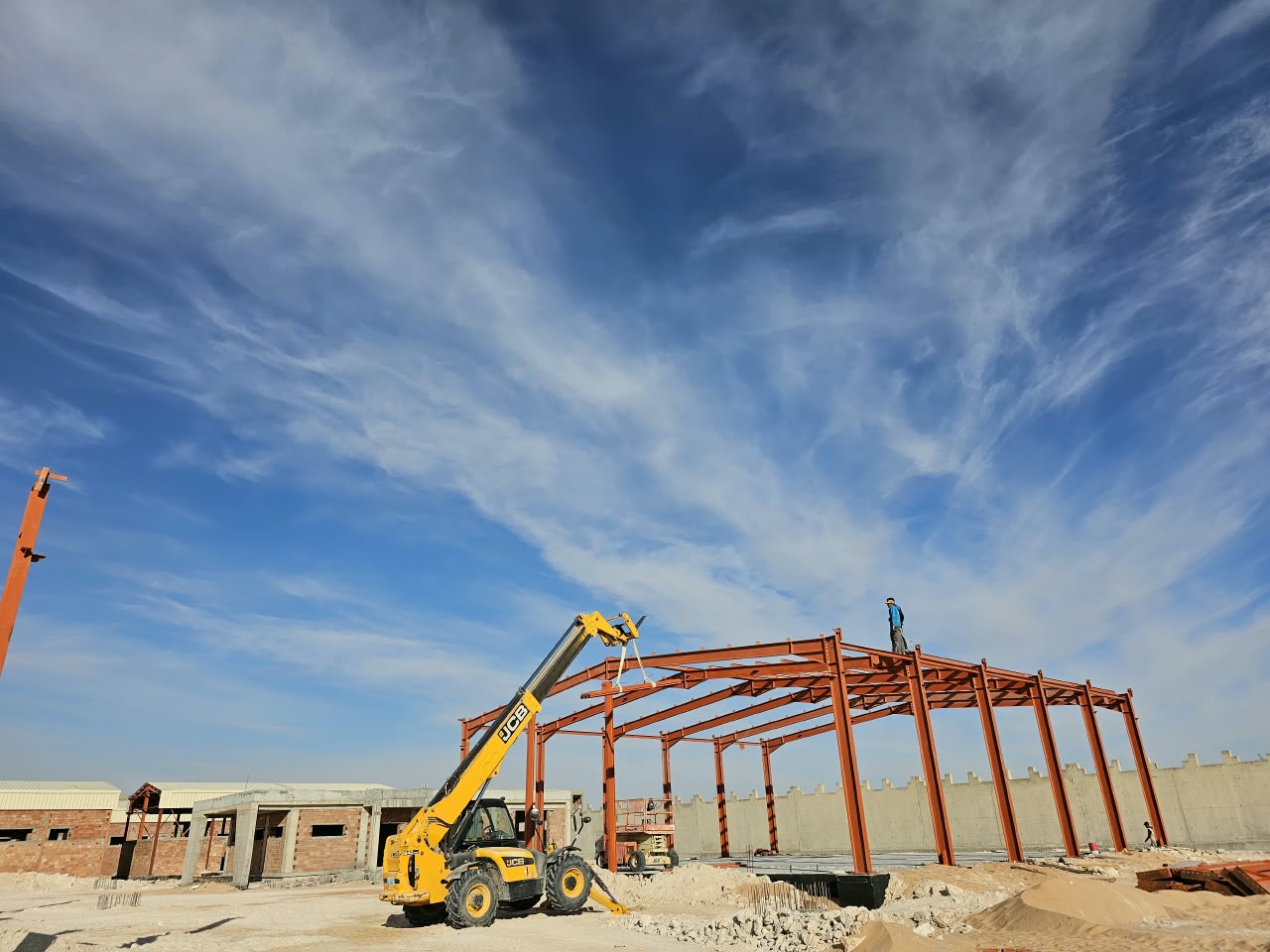 Montage d'une charpente métallique avec un chariot télescopique JCB sur un chantier de Hassi Messaoud